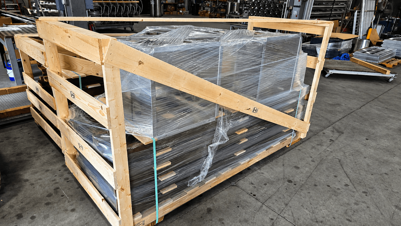 Shrink-wrapped and banded assemblies secured in a custom wooden crate on the shop floor