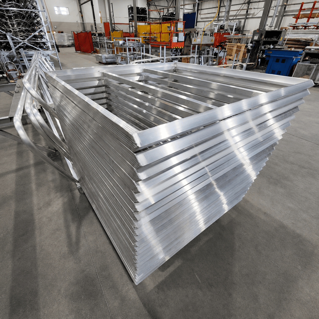 Stack of finished welded aluminum frame assemblies on the FWM shop floor