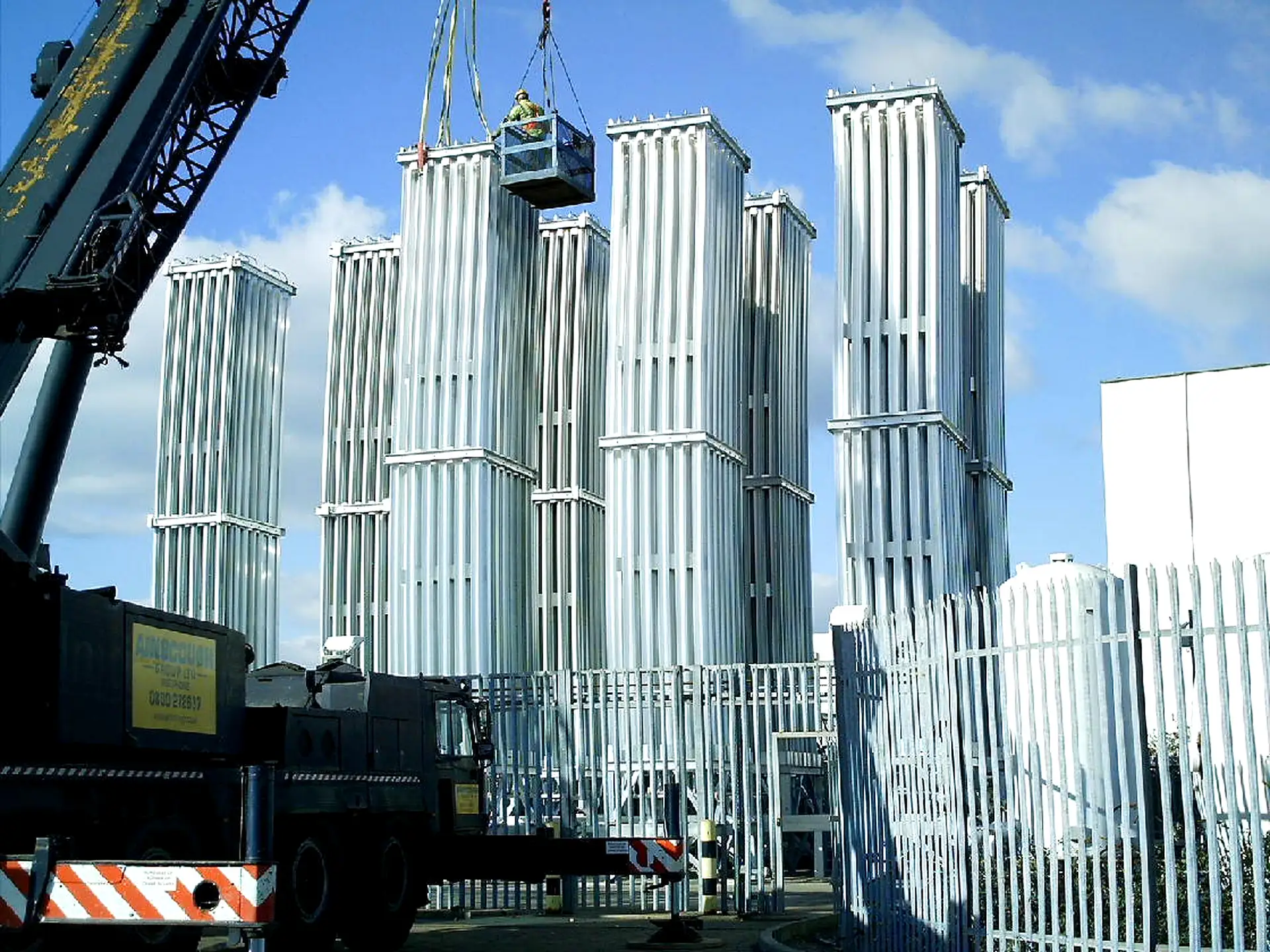 A crane setting tall finned-aluminum FWM AV Series vaporizer towers during a field installation