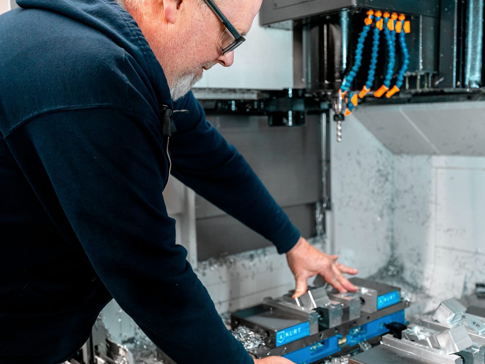 A CNC machining center cutting an aluminum part under flood coolant at FWM