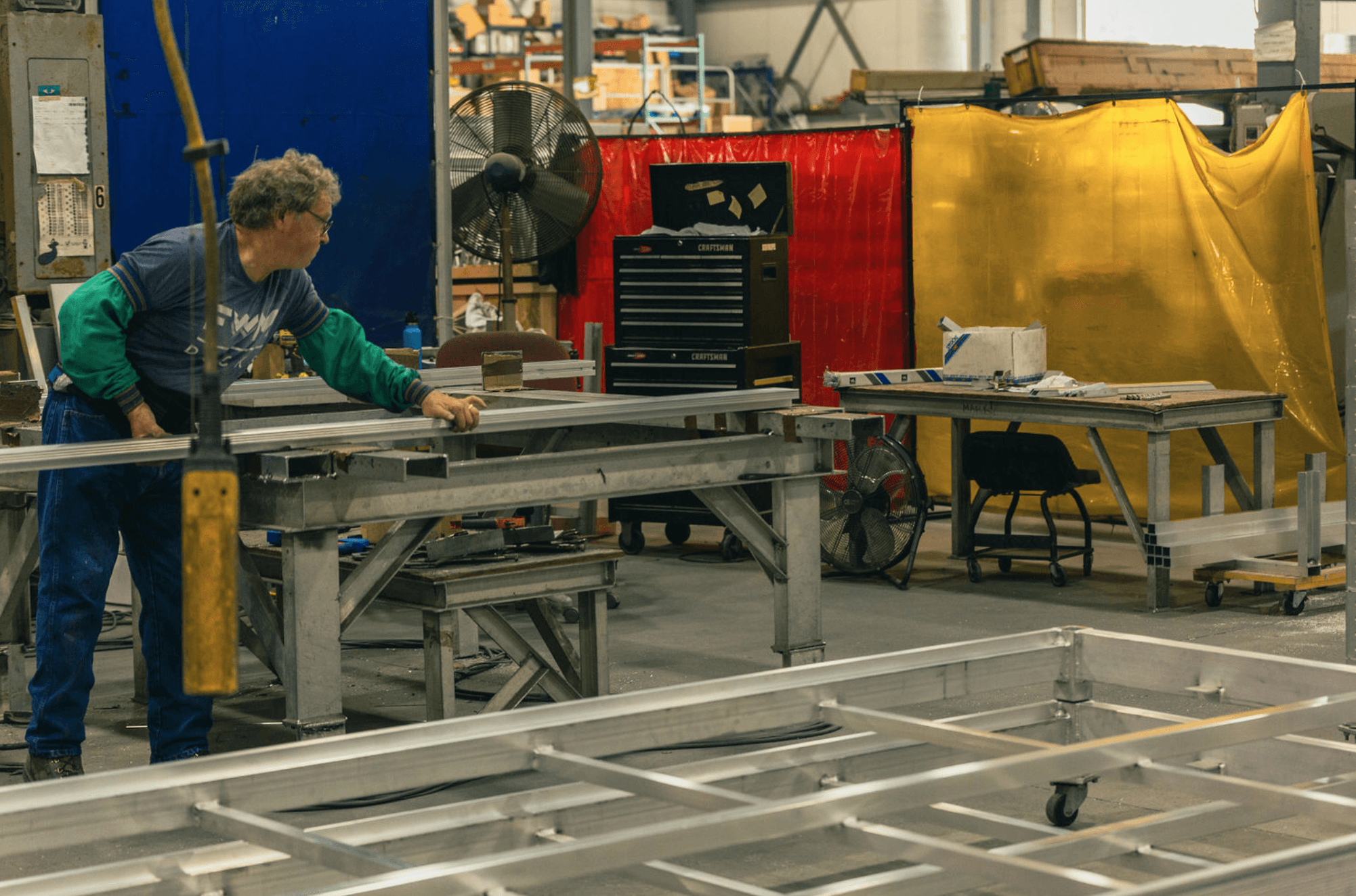 An FWM worker aligning an aluminum extrusion on a fixture table during assembly fit-up