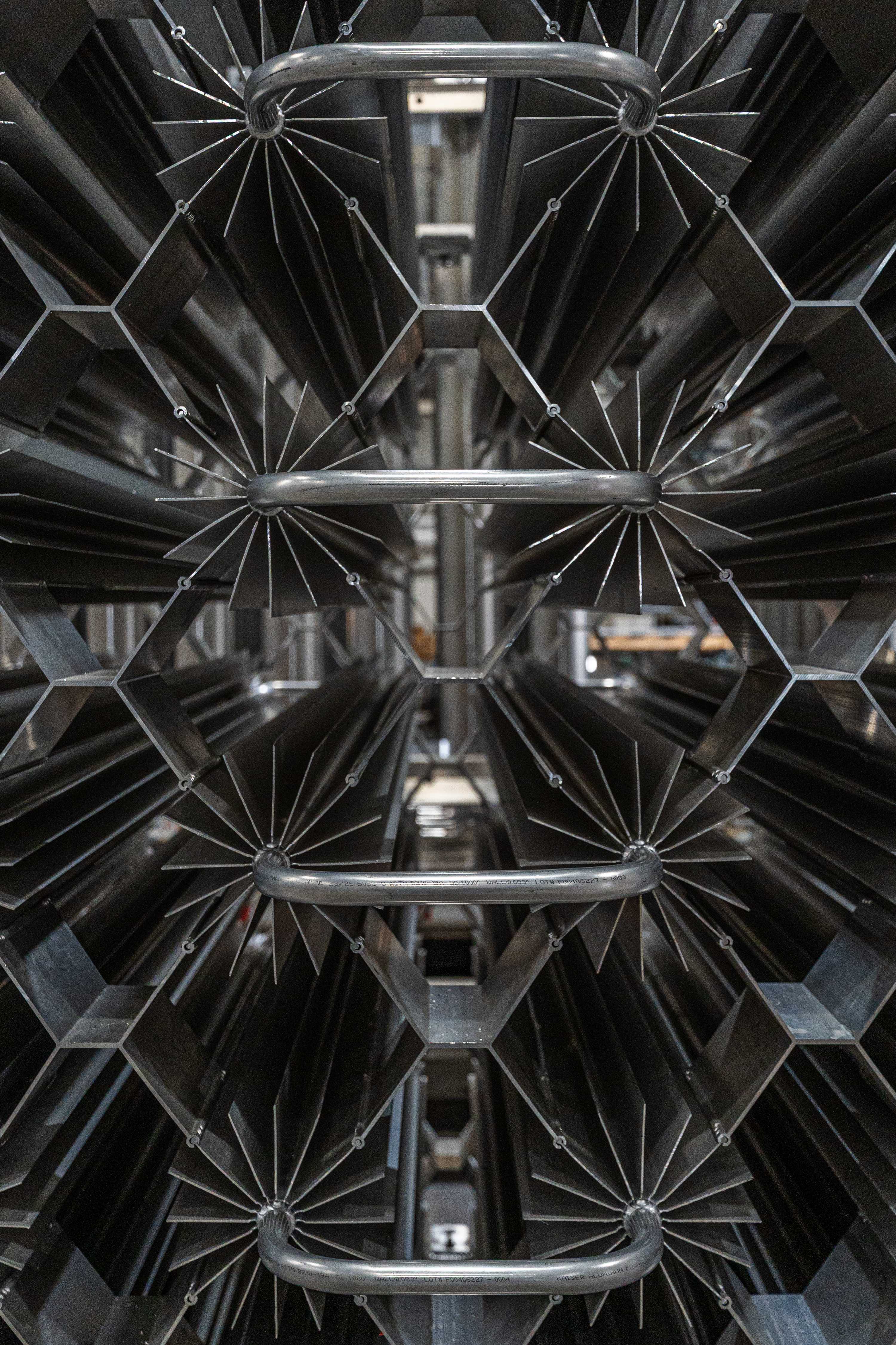 A dark macro view of nested star-fin aluminum extrusions at FWM showing the material in finished form