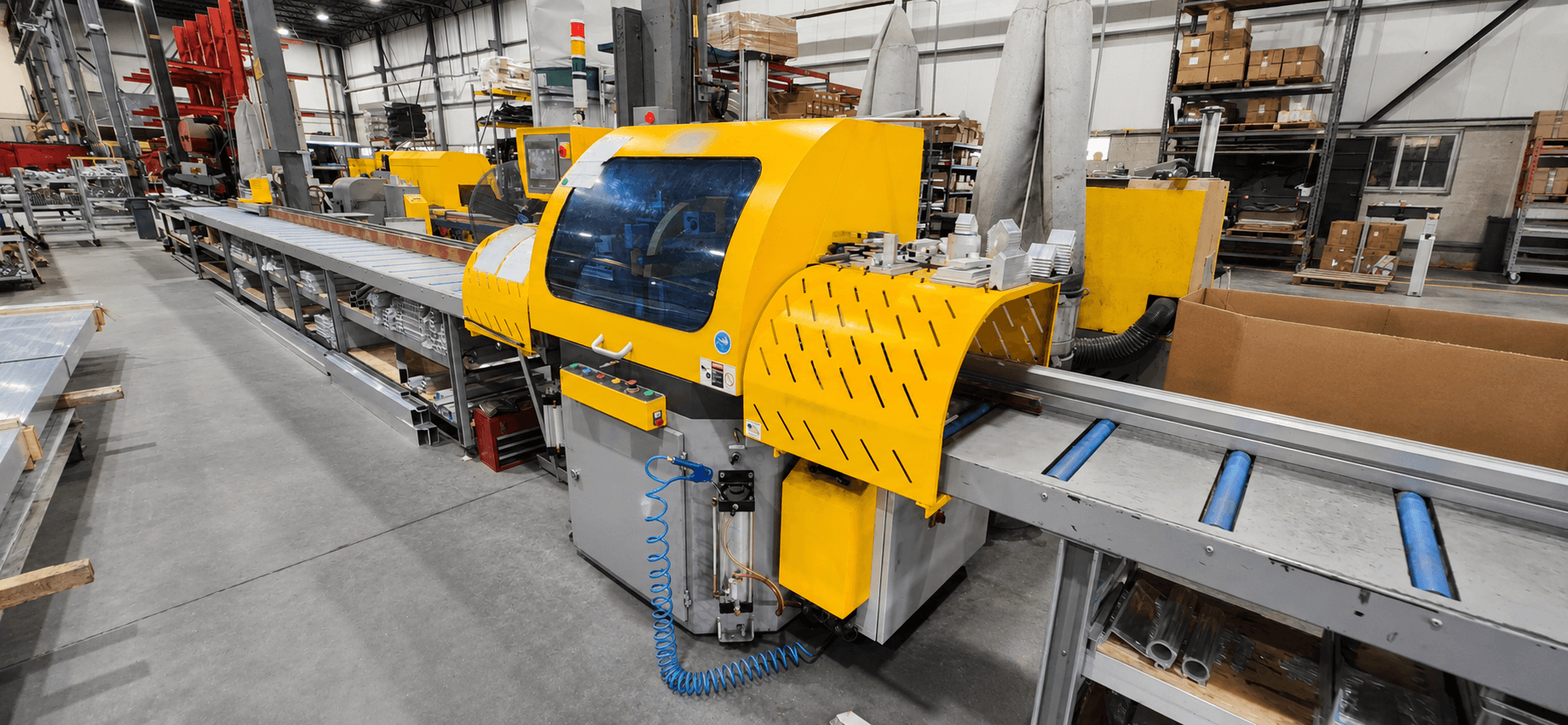 A CNC aluminum cutting saw and conveyor line running on the FWM shop floor in Hudson, NH